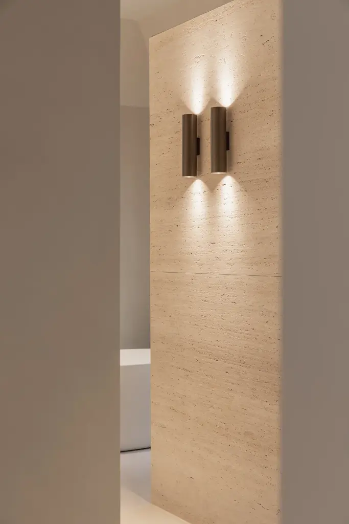 Bronzen wandlamp tegen een travertijnen wand, Gezinsvilla in Heusden-Zolder, interieur Laura Calleeuw