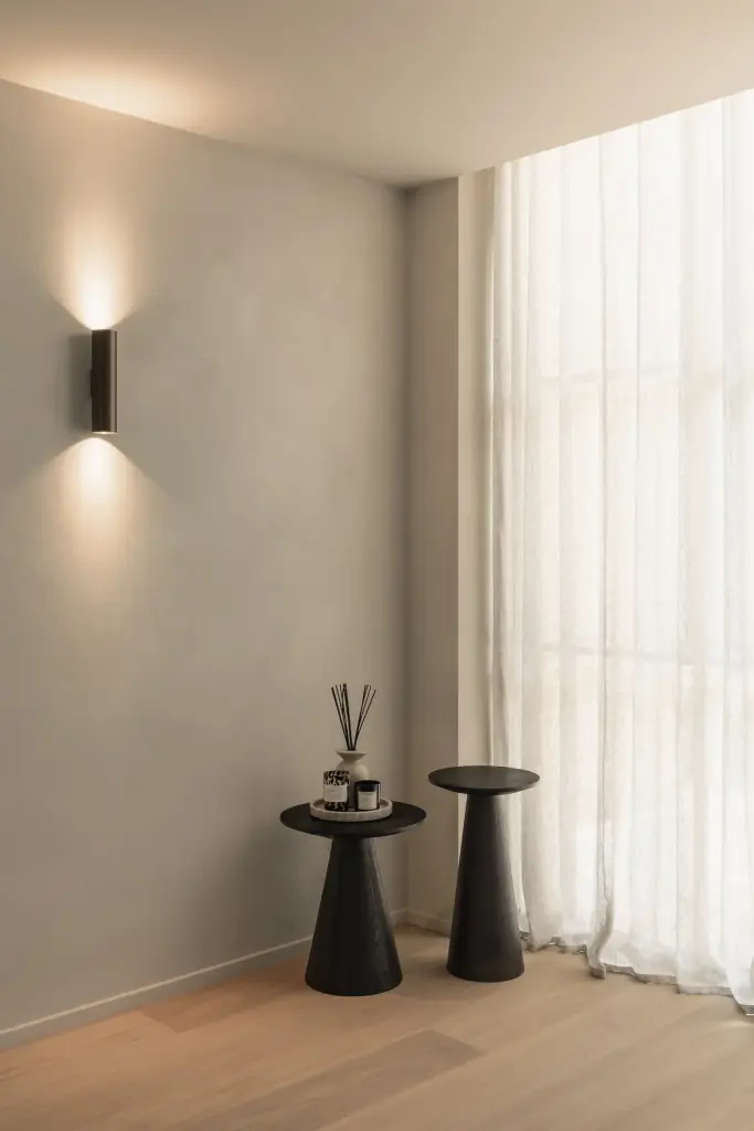 Wandlamp boven kleine zwarte zijtafeltjes naast lange vitrage, Gezinsvilla in Heusden-Zolder, interieur Laura Calleeuw
