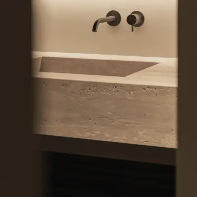 Travertijnen wastafel met wandkranen in een donkere nis, Gezinsvilla in Heusden-Zolder, interieur Laura Calleeuw