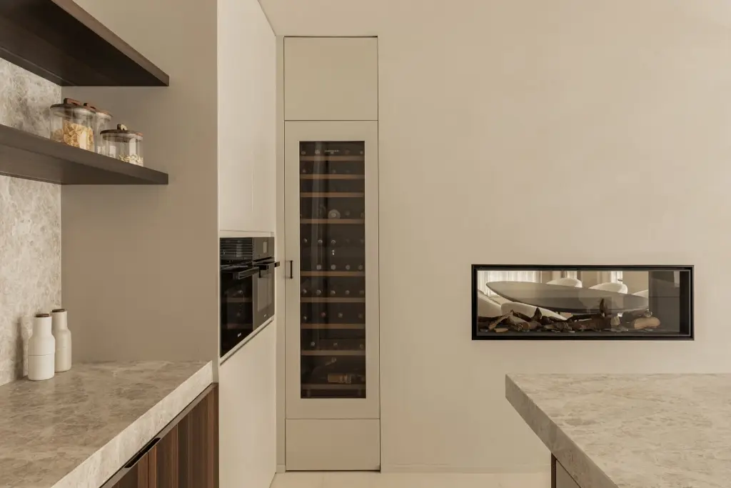 Wijnklimaatkast en inbouwoven naast een lage open haard in de keuken, Gezinsvilla in Heusden-Zolder, interieur Laura Calleeuw