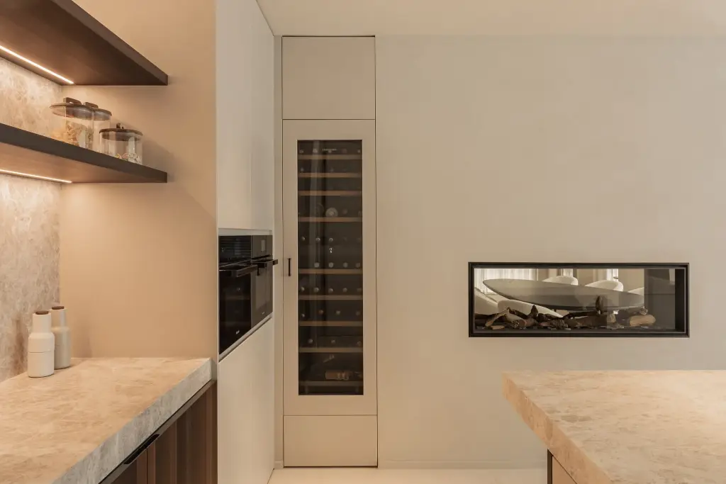 Wijnklimaatkast en inbouwoven naast een lage open haard in de keuken, Gezinsvilla in Heusden-Zolder, interieur Laura Calleeuw
