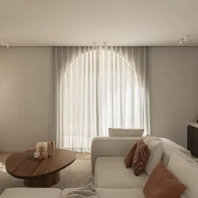 Zithoek met boogvormig raam, lage ovale salontafel in notelaar en hoeksofa, Gezinsvilla in Heusden-Zolder, interieur Laura Calleeuw