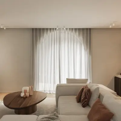 Zithoek met boogvormig raam, lage ovale salontafel in notelaar en hoeksofa, Gezinsvilla in Heusden-Zolder, interieur Laura Calleeuw