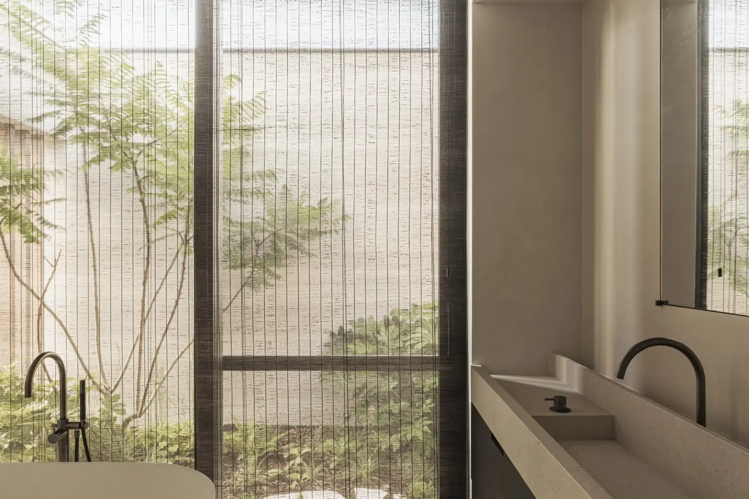 Zicht op de patio vanuit de badkamer met bad en een lange natuurstenen wastafel, a home that invites you to slow down, interieur Laura Calleeuw