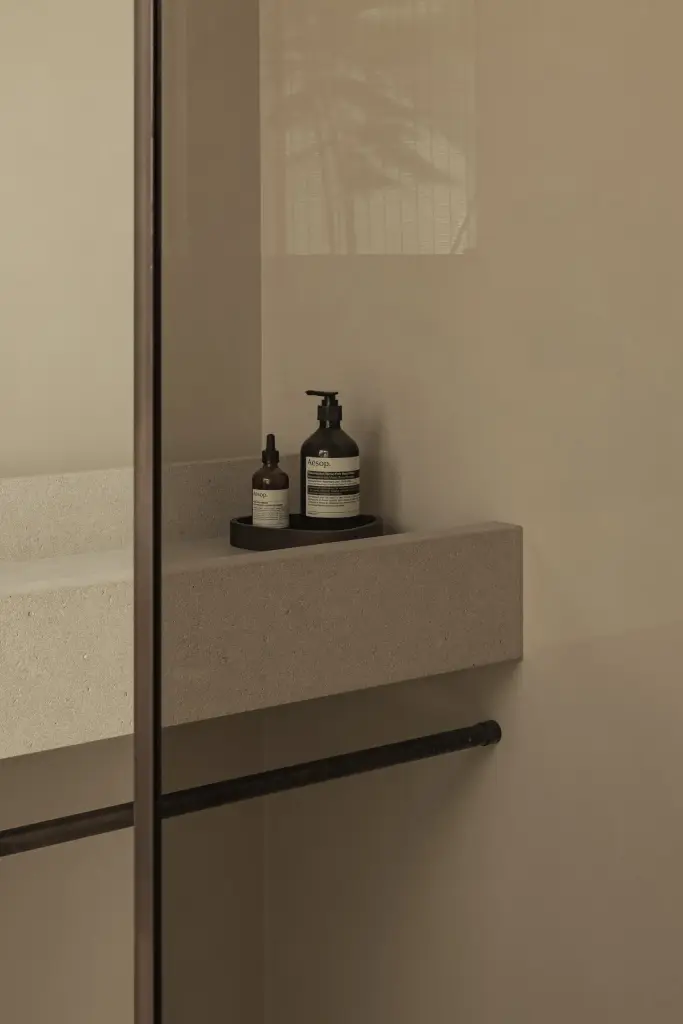 Tablet met zeep en handcrème naast een glaswand in de badkamer, a home that invites you to slow down, interieur Laura Calleeuw