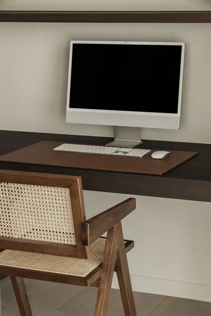 Bureau met computer en een houten stoel met rieten rug, a home that invites you to slow down, interieur Laura Calleeuw