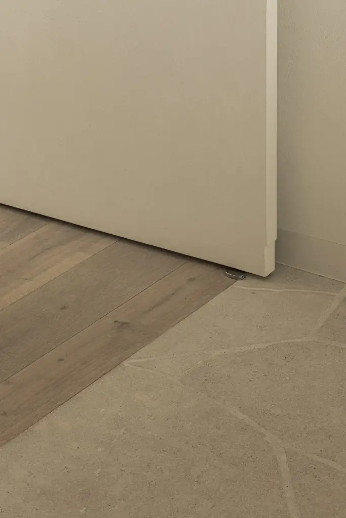 Overgang tussen natuursteen en eikenhouten vloer bij een vlakke deur, a home that invites you to slow down, interieur Laura Calleeuw