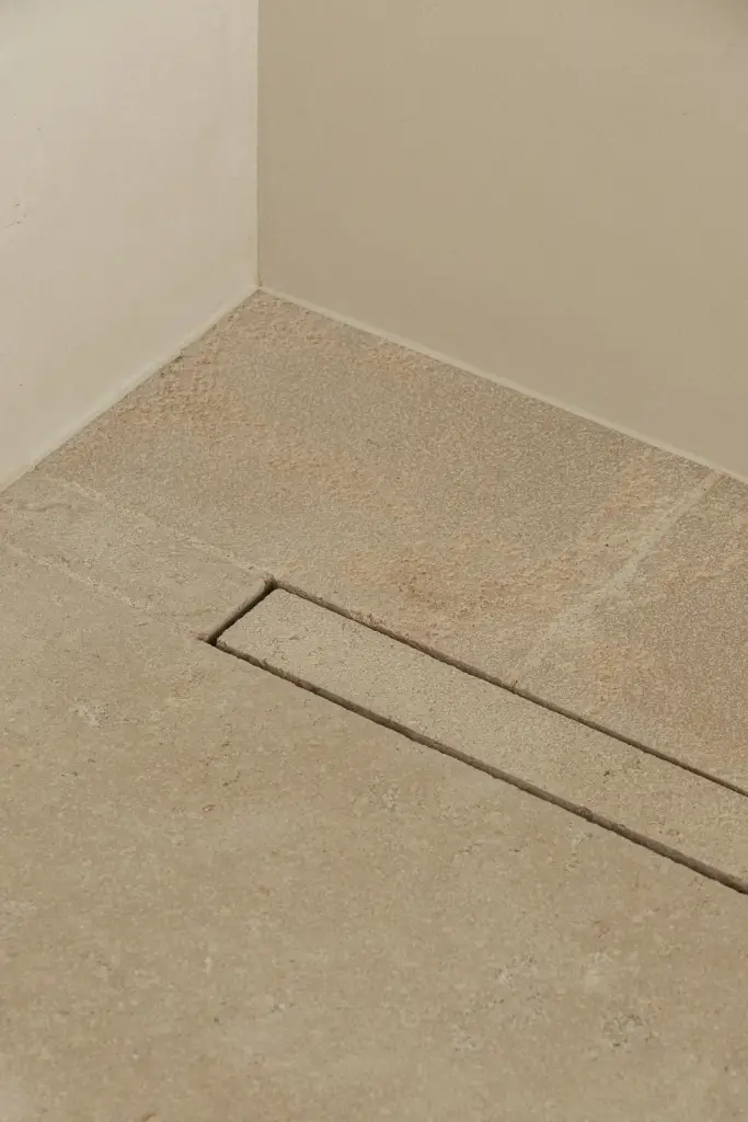 Douchevloer in natuursteen met een lijnafvoer, a home that invites you to slow down, interieur Laura Calleeuw