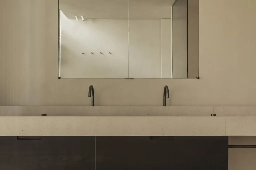 Dubbele wastafel met zwarte kranen onder een spiegelkast, a home that invites you to slow down, interieur Laura Calleeuw