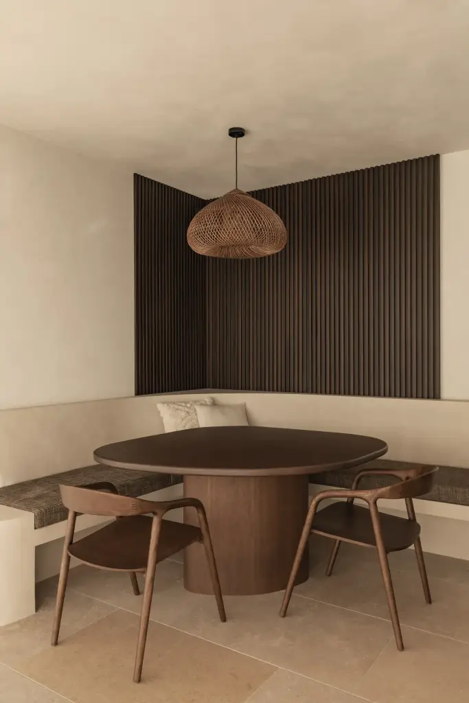 Eethoek met ronde houten tafel, stoelen, hoekbank en rotan hanglamp, a home that invites you to slow down, interieur Laura Calleeuw