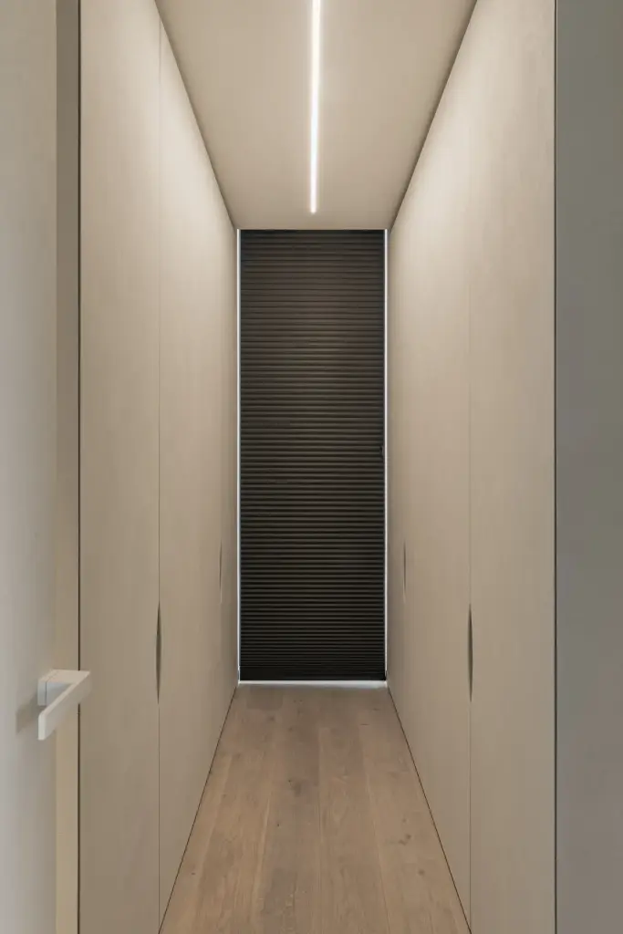Gang met lichtlijn, kastenwand en een houten ribbeldeur op het einde, a home that invites you to slow down, interieur Laura Calleeuw