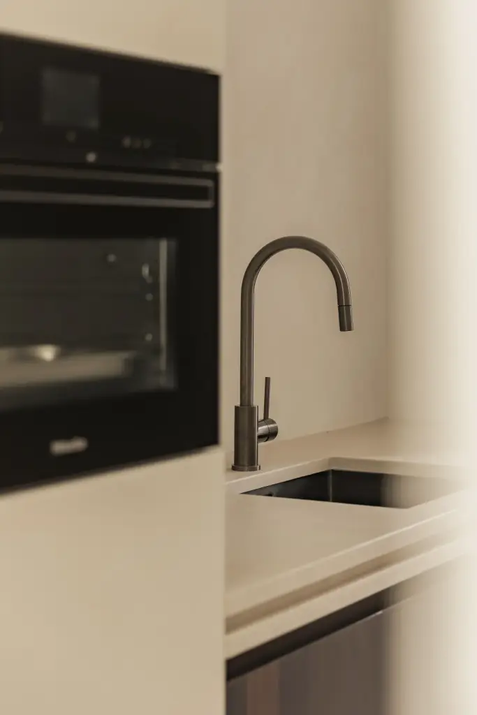 Inbouwoven en spoelbak met zwarte kraan in de keuken, a home that invites you to slow down, interieur Laura Calleeuw