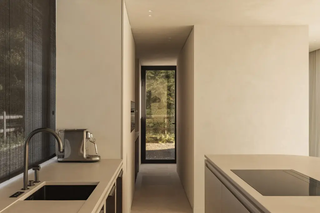 Keuken met spoelbak, koffiemachine en doorkijk door de gang naar een glazen deur, a home that invites you to slow down, interieur Laura Calleeuw