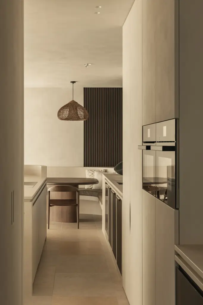 Keuken met inbouwoven, doorkijk naar de eethoek en een rotan hanglamp, a home that invites you to slow down, interieur Laura Calleeuw