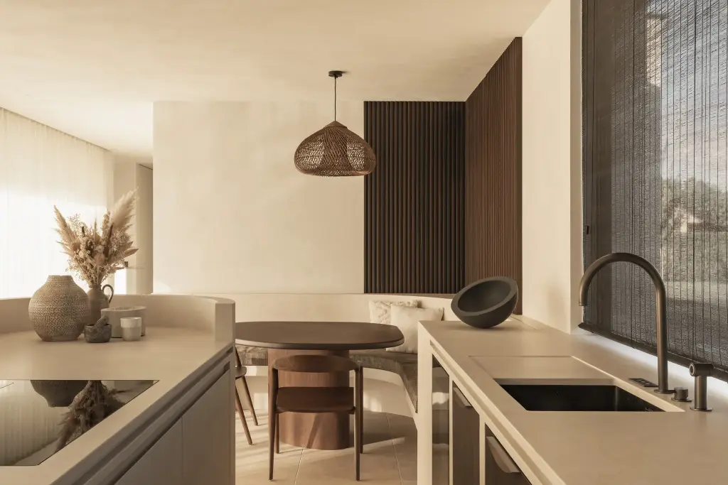 Keuken met rotan hanglamp, houten ribbelwand en eettafel op de achtergrond, a home that invites you to slow down, interieur Laura Calleeuw