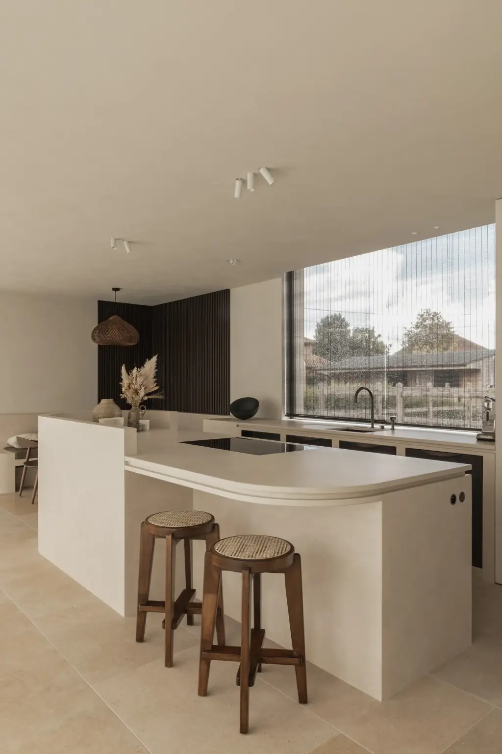 Keuken met kookeiland, twee houten krukken en een groot raam, a home that invites you to slow down, interieur Laura Calleeuw