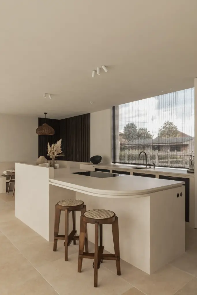 Keuken met kookeiland, twee houten krukken en een groot raam, a home that invites you to slow down, interieur Laura Calleeuw