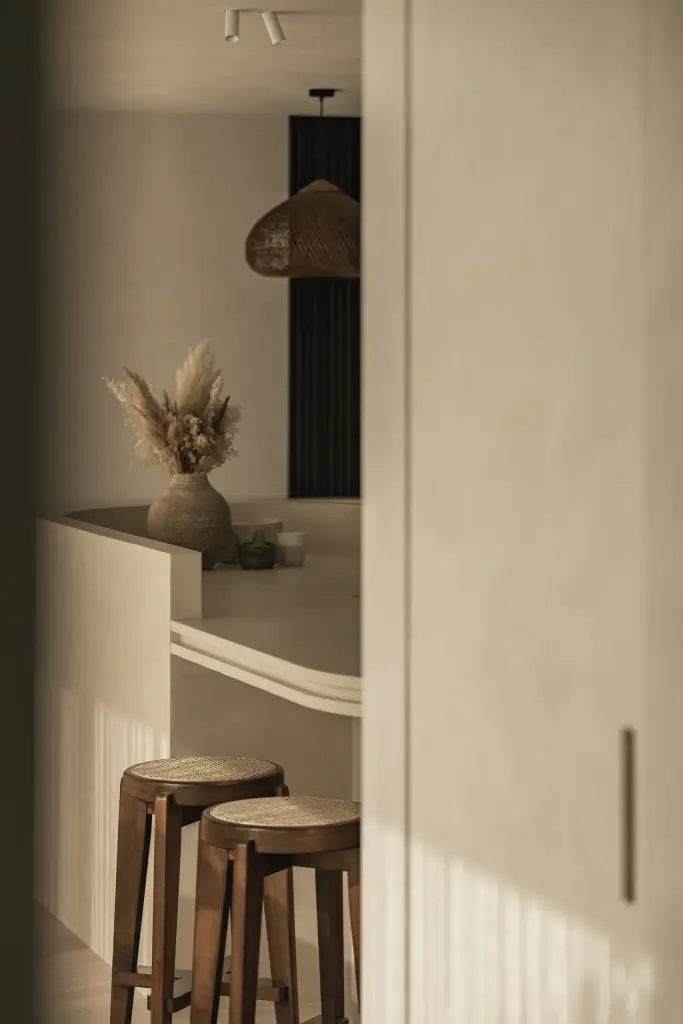 Kookeiland met krukken en droogbloemen naast een hoge kastdeur in kalkpleister, a home that invites you to slow down, interieur Laura Calleeuw