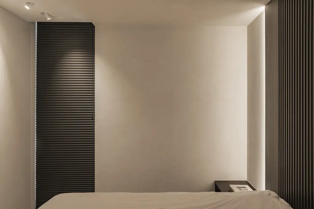 Slaapkamer met bed, houten ribbelwand en een lichtlijn langs de wand, a home that invites you to slow down, interieur Laura Calleeuw