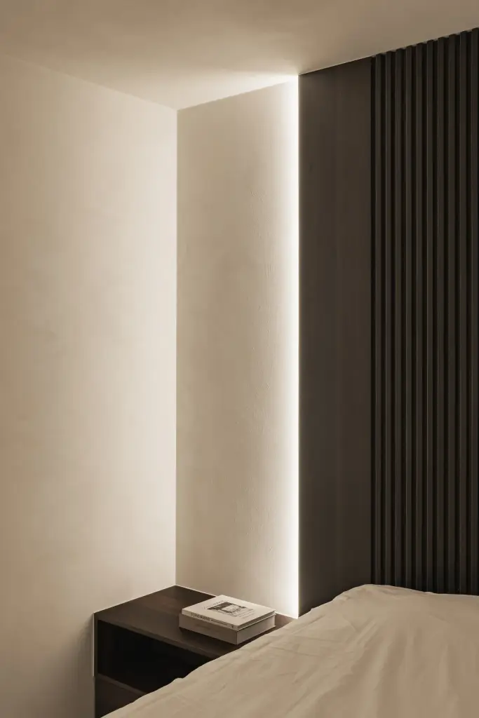 Bed met nachtkastje tegen een houten ribbelwand en een lichtlijn, a home that invites you to slow down, interieur Laura Calleeuw