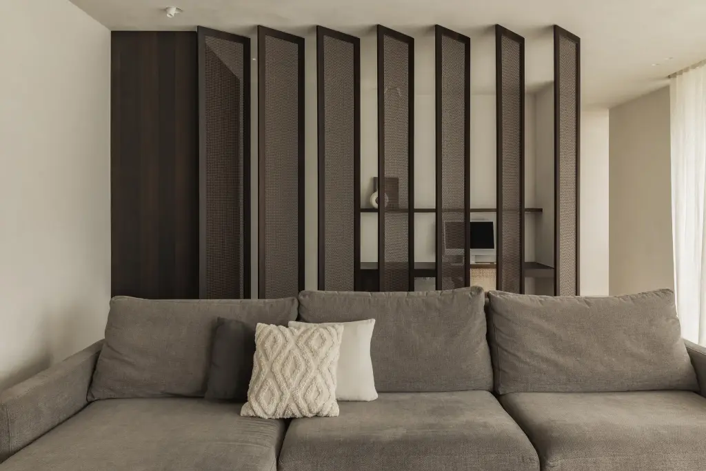 Sofa voor een lamellenwand in donker hout met zicht op het bureau erachter, a home that invites you to slow down, interieur Laura Calleeuw