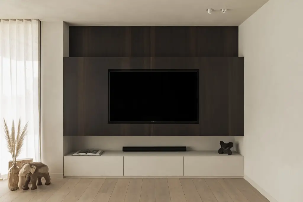 Televisiewand in donker hout met laag meubel, houten olifantjes en pampasgras, a home that invites you to slow down, interieur Laura Calleeuw