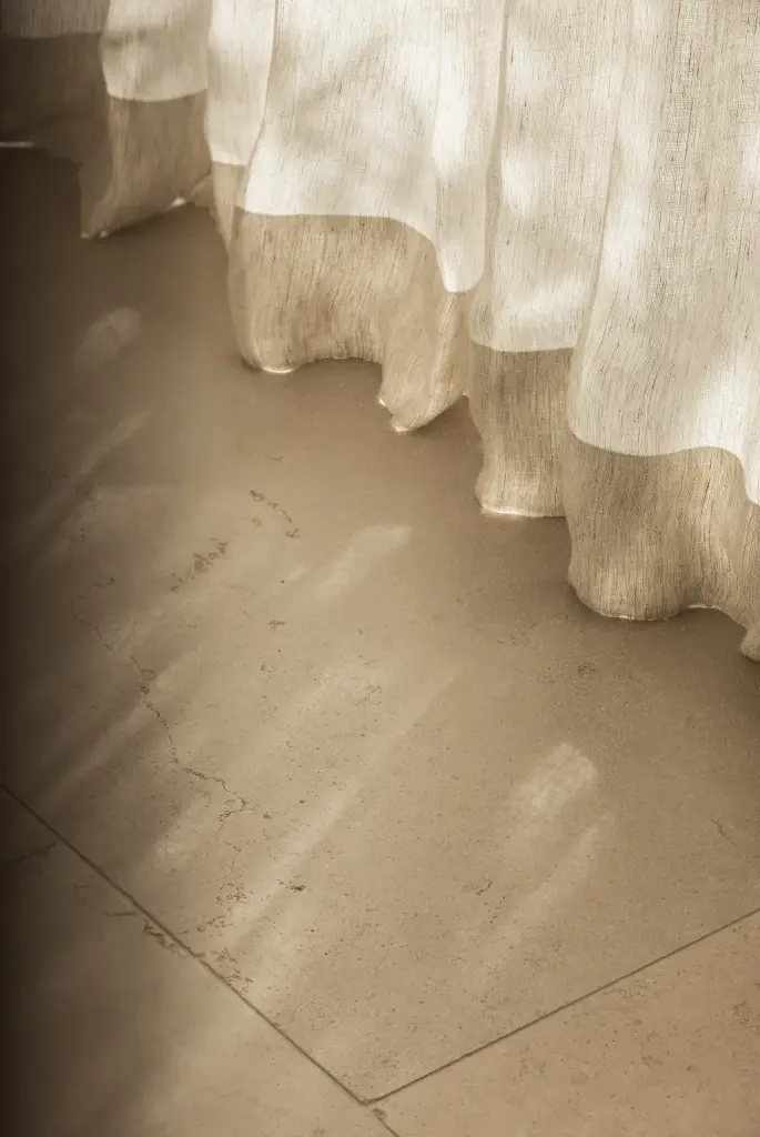 Zonlicht op een natuurstenen vloer onder een linnen vitrage, a home that invites you to slow down, interieur Laura Calleeuw