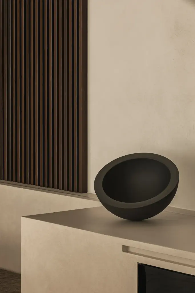 Zwarte schaal op het kookeiland voor een houten ribbelwand, a home that invites you to slow down, interieur Laura Calleeuw