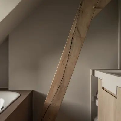 Badkamer onder de dakhelling met een zichtbare houten balk en inbouwbad, Hoeve in Westkapelle, interieur Laura Calleeuw