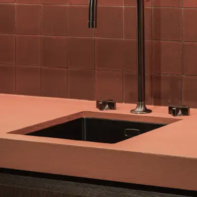 Spoelbak met zwarte kraan in een terracotta werkblad en tegelwerk, Hoeve in Westkapelle, interieur Laura Calleeuw