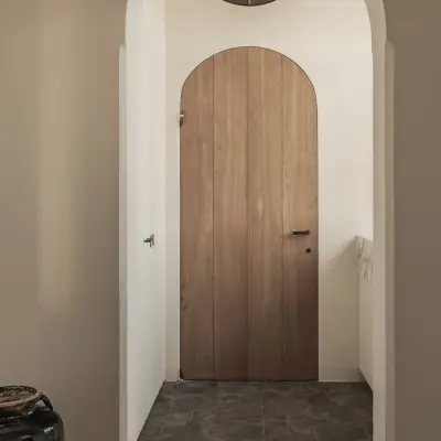 Boogvormige doorgang met een houten boogdeur en een vloer in zeshoekige tegels, Hoeve in Westkapelle, interieur Laura Calleeuw