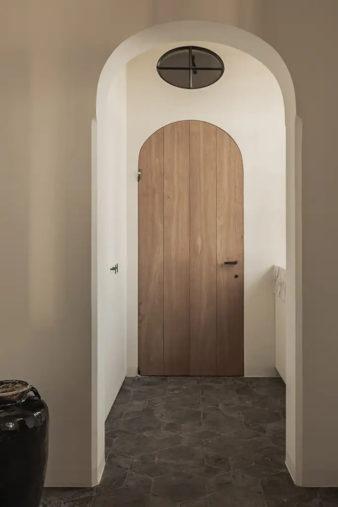 Boogvormige doorgang met een houten boogdeur en een vloer in zeshoekige tegels, Hoeve in Westkapelle, interieur Laura Calleeuw