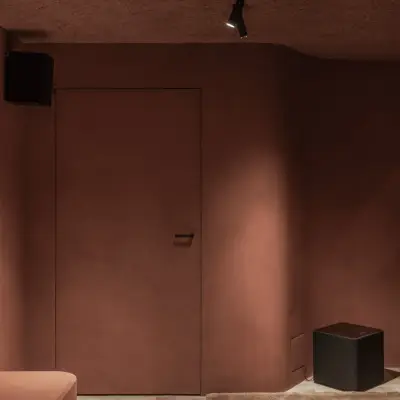 Vlakke deur in de terracotta wand naast een subwoofer, Hoeve in Westkapelle, interieur Laura Calleeuw