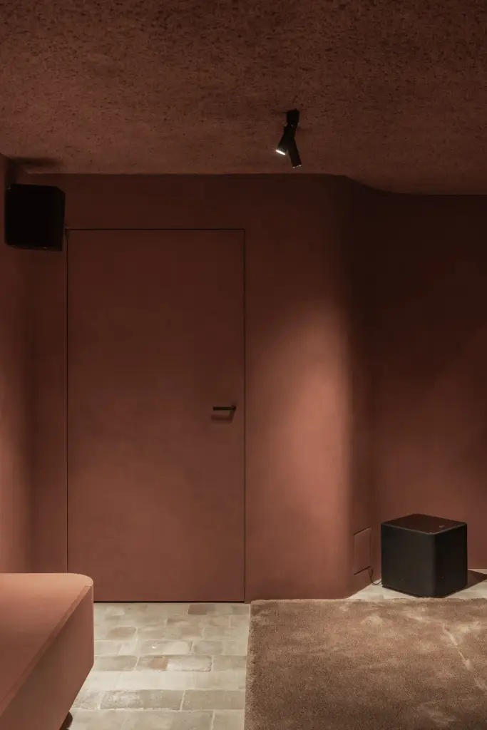 Vlakke deur in de terracotta wand naast een subwoofer, Hoeve in Westkapelle, interieur Laura Calleeuw