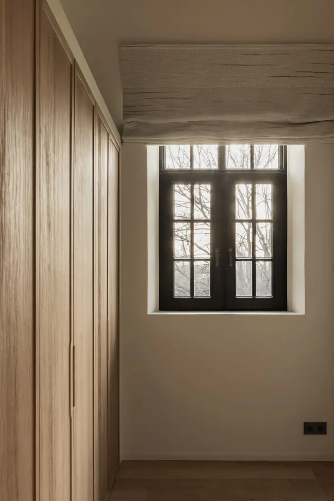Kast in eikenhout naast een zwart raam met roman blind, Hoeve in Westkapelle, interieur Laura Calleeuw