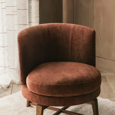 Fauteuil in roestkleurig fluweel met draaivoet in hout op een wit tapijt, Hoeve in Westkapelle, interieur Laura Calleeuw