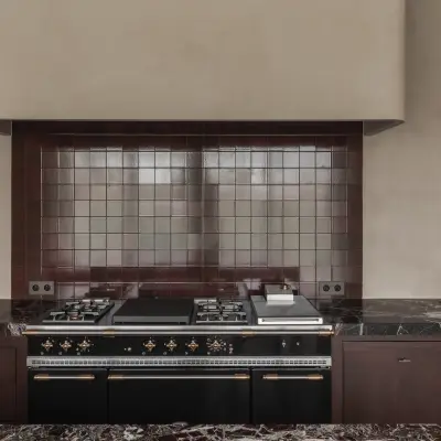 Fornuis met bordeauxkleurig tegelwerk onder een gepleisterde schouw in de keuken, Hoeve in Westkapelle, interieur Laura Calleeuw