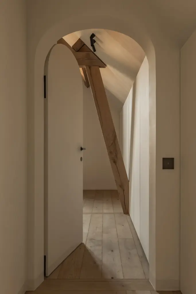 Gang met witte boogdeur en een houten balk, Hoeve in Westkapelle, interieur Laura Calleeuw