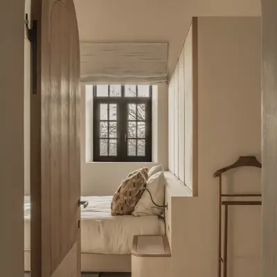 Houten boogdeur met zicht op de slaapkamer met roman blind, Hoeve in Westkapelle, interieur Laura Calleeuw