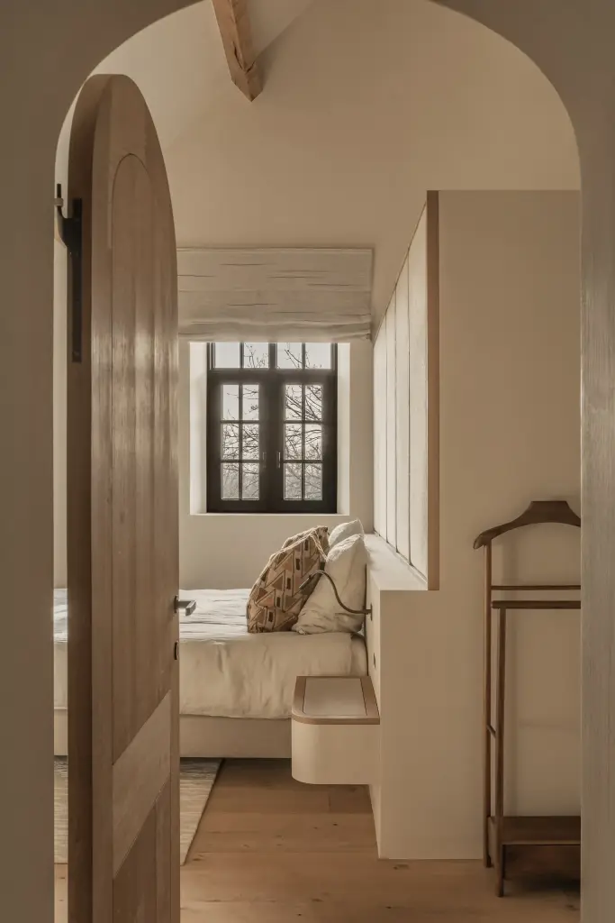 Houten boogdeur met zicht op de slaapkamer met roman blind, Hoeve in Westkapelle, interieur Laura Calleeuw