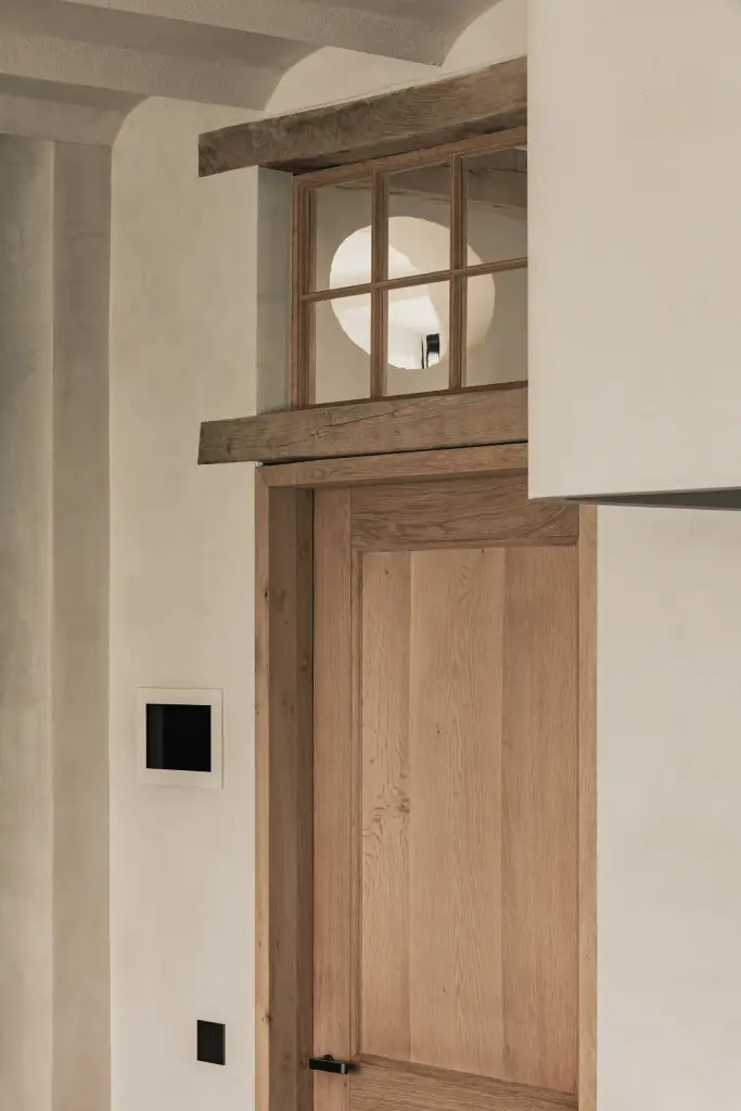 Houten deur onder een ronde lichtopening en een houten latei, Hoeve in Westkapelle, interieur Laura Calleeuw