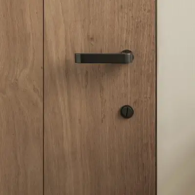 Detail van een eikenhouten deur met zwarte klink, Hoeve in Westkapelle, interieur Laura Calleeuw