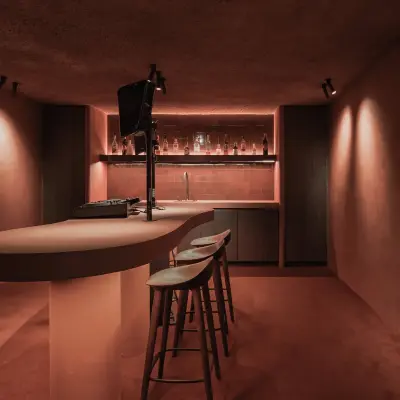 Kelderbar in terracotta met ronde toog, barkrukken en verlichte flessenwand, Hoeve in Westkapelle, interieur Laura Calleeuw