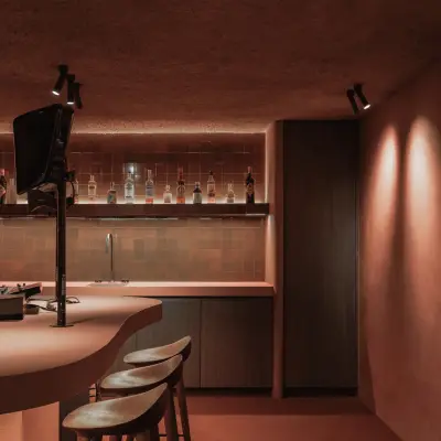 Kelderbar met toog, barkrukken, televisie en flessenwand, Hoeve in Westkapelle, interieur Laura Calleeuw
