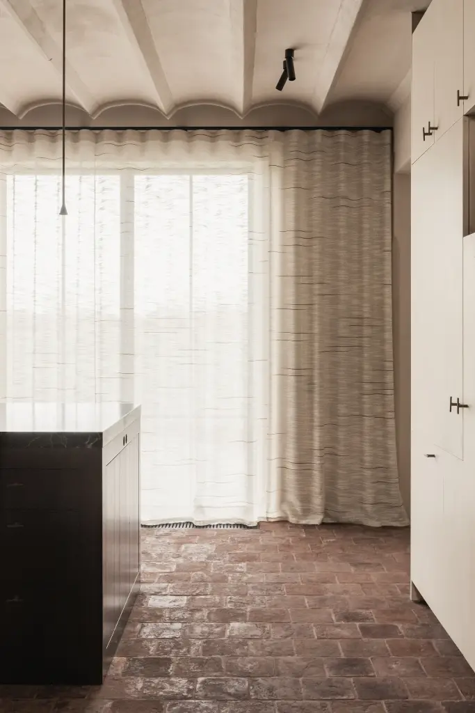 Kookeiland voor een raam met vitrage op een terracotta vloer, Hoeve in Westkapelle, interieur Laura Calleeuw