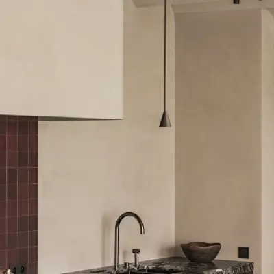 Keuken met zwarte kraan, werkblad en een gepleisterde schouw met hanglampen, Hoeve in Westkapelle, interieur Laura Calleeuw
