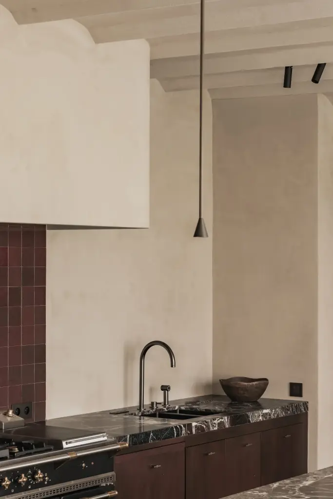 Keuken met zwarte kraan, werkblad en een gepleisterde schouw met hanglampen, Hoeve in Westkapelle, interieur Laura Calleeuw