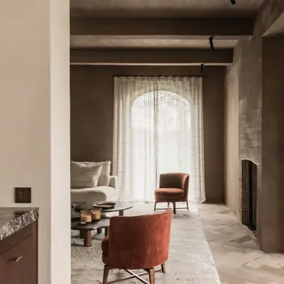 Leefruimte met boogvormig raam, roestkleurige fauteuil en visgraatparket, Hoeve in Westkapelle, interieur Laura Calleeuw