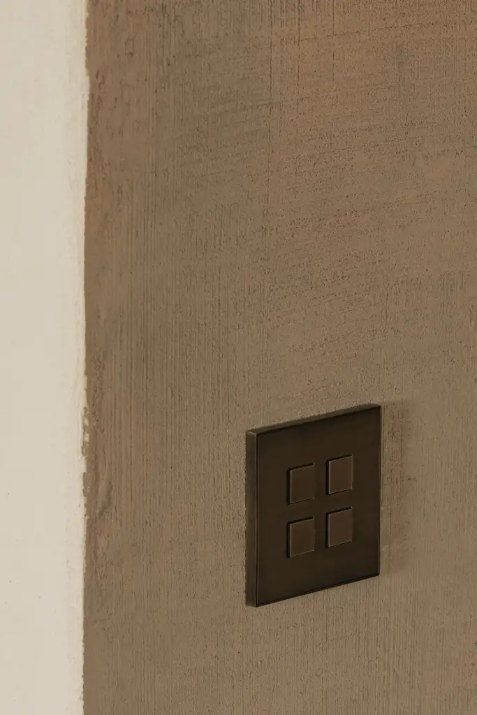Detail van een bronzen lichtschakelaar op een leempleisterwand, Hoeve in Westkapelle, interieur Laura Calleeuw