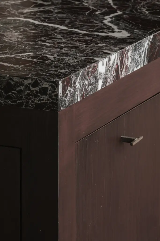 Detail van het rood-witte marmeren werkblad boven een houten lade met greep, Hoeve in Westkapelle, interieur Laura Calleeuw